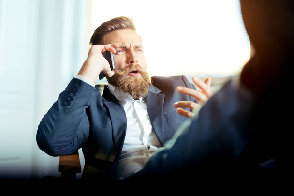 Portrait of businessman talking on mobile phone in office - Fotoğraf, Görsel