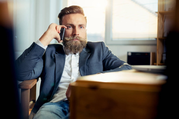 Portrait of businessman talking on mobile phone in office - Foto, Bild