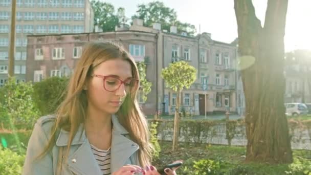Uma jovem caminhando e usando um smartphone
 - Filmagem, Vídeo