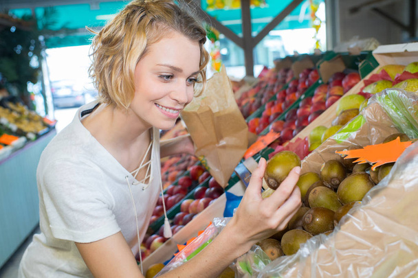 female customer with little choosing fruits in food shop - Foto, immagini