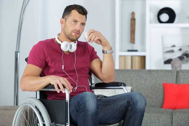 Man in wheelchair with headphones around his neck - Fotoğraf, Görsel