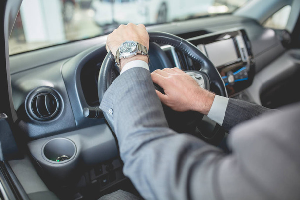 Mans hands on steering wheel of new electro car. - Foto, Imagen