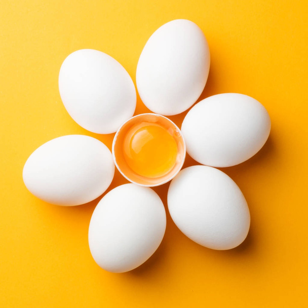 White eggs and egg yolk on the yellow background. topview, square - Zdjęcie, obraz