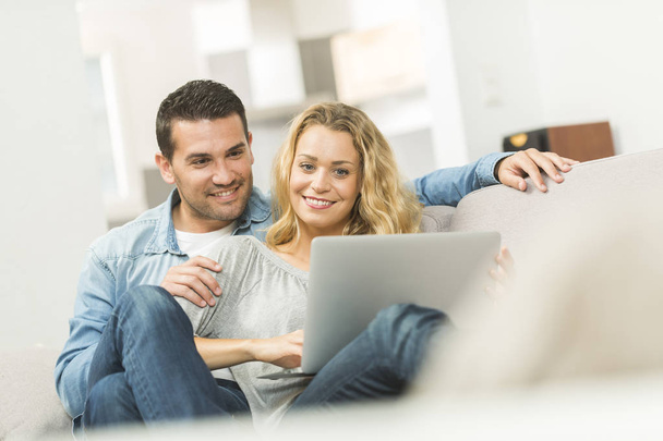 Happy young couple watching internet on their laptop - Foto, imagen