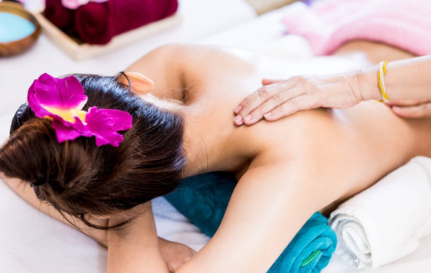 Woman is getting oil massage on her back in tropical Spa - Photo, Image