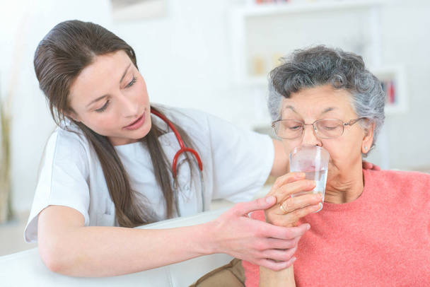 giving senior lady a glass of water - Fotó, kép