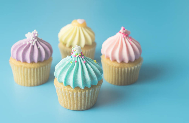 Kleurrijke Pastel Cupcake op blauwe pastel achtergrond met blauwe cupcake op focus - Foto, afbeelding