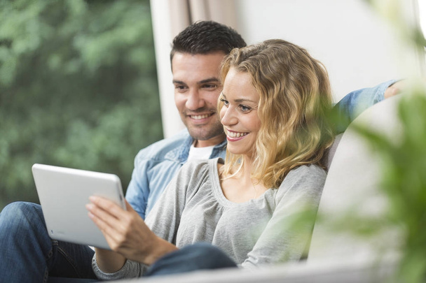 Happy young couple watching internet on their tablet - Photo, Image