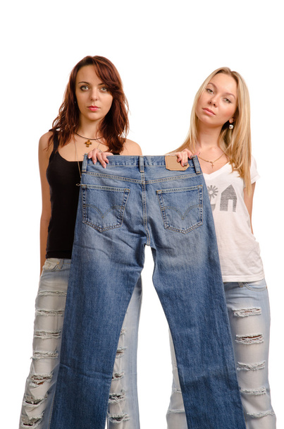 dwóch młodych kobiet, trzyma się parę dżinsów - Zdjęcie, obraz