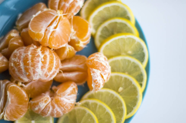 Piatto blu con limone e mandarino a fette
 - Foto, immagini