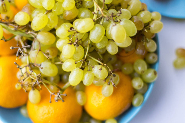 Prato azul com uvas de frutas com tangerina
 - Foto, Imagem