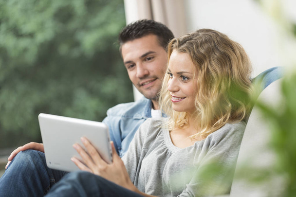 Happy young couple watching internet on their tablet - Foto, Imagem