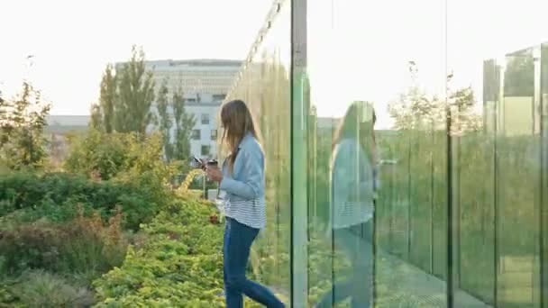 Una joven dama caminando y usando un teléfono al aire libre
 - Metraje, vídeo