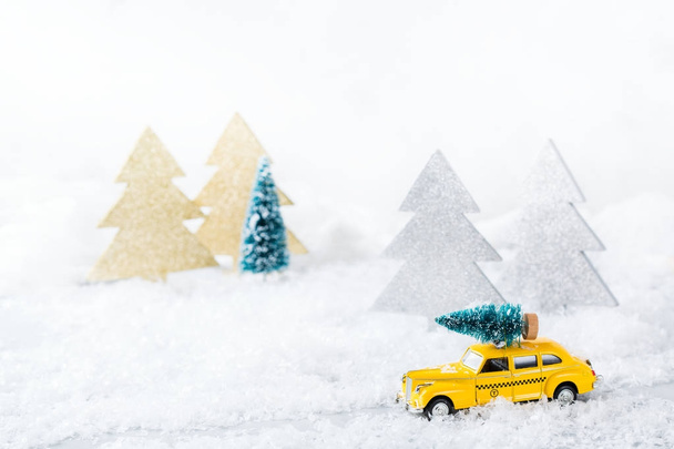 Hračka auto přepravující vánoční strom v lese sněhu - Fotografie, Obrázek