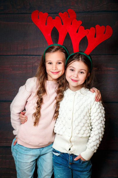 Two happy little smiling girls .Christmas concept. Smiling funny sisters in deer horns in studio. - Photo, Image