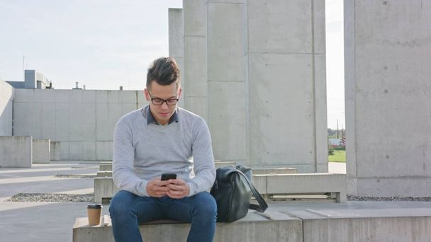 A Young Man Using a Phone Outside - Foto, afbeelding