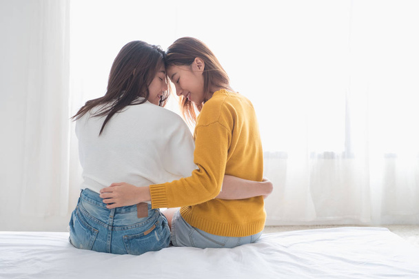 Asia lesbian lgbt couple hug and sitting on bed near white windo - Фото, изображение