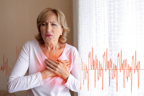 Mature woman suffering from heart attack at home - Photo, image