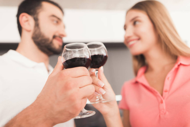 A man and a woman are drinking wine in the kitchen. They hold glasses of wine in their hands. - Foto, afbeelding