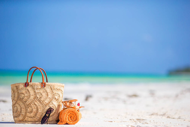 Strandzubehör - Spielzeugflugzeug, Strohtasche, orangefarbenes Handtuch und Sonnenbrille am Strand - Foto, Bild