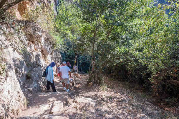 pessoas descendo escadas de pedra em direção a caverna do Abismo do Céu no distrito de Silifke, Mersin
 - Foto, Imagem