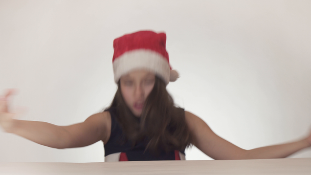 Güzel yaramaz kız genç bir Noel Baba şapkalı duygusal beyaz arka plan stok görüntüleri video şarkı söylüyor. - Video, Çekim