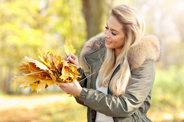 Happy woman playing with autumn leaves outdoors - Fotoğraf, Görsel