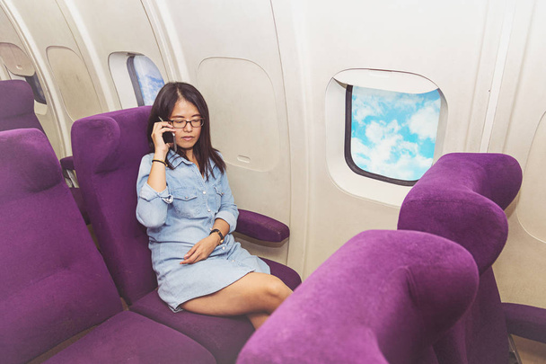 Asian woman use of mobile phone inside airplane - Foto, afbeelding