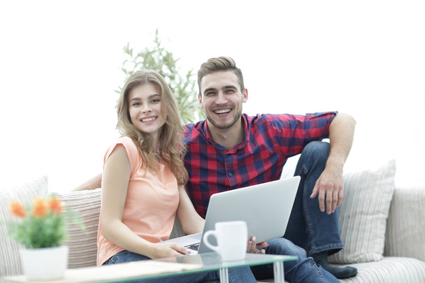 young couple of students uses a laptop sitting on sofa - Zdjęcie, obraz