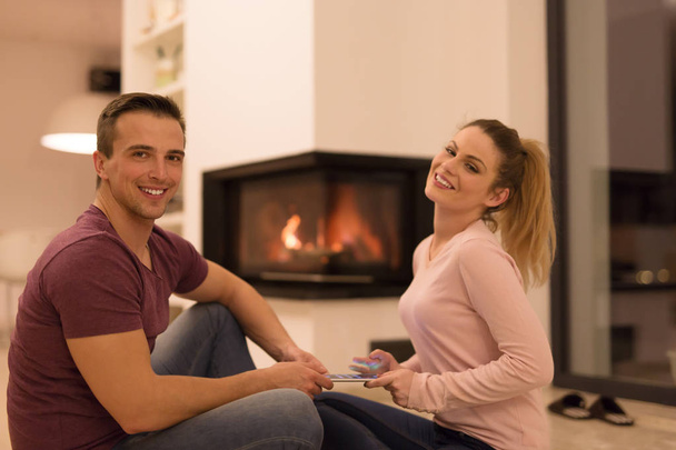 Couple on floor in front of fireplace  - Фото, зображення