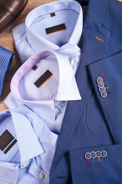 set klassieke herenkleding - blauw pak, shirts, bruine schoenen, riem en stropdas op houten achtergrond. - Foto, afbeelding