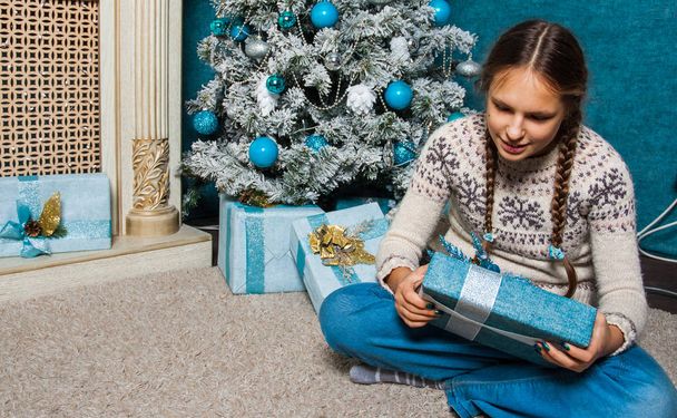 teenager girl hold presents gift box on Christmas tree background - Photo, Image
