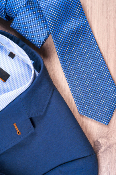 Klasik erkek kıyafetleri - mavi takım, gömlekler, kahverengi ayakkabılar, kemer ve kravat ahşap arka planda. - Fotoğraf, Görsel