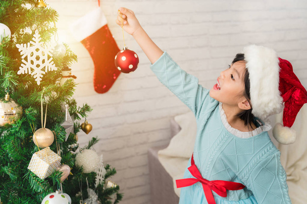 little child girl is decorating the Christmas tree - Φωτογραφία, εικόνα