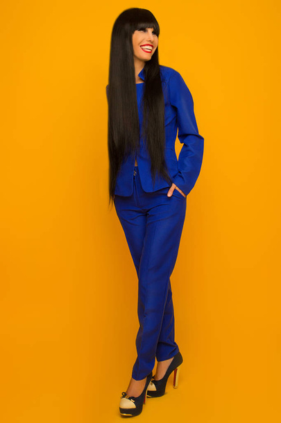 girl with black long hair in a blue suit posing  - Foto, Imagen