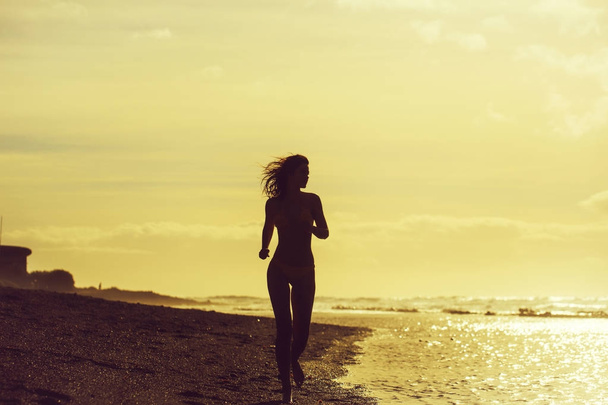Pretty girl in yellow swimsuit running on sandy beach - Foto, Imagen