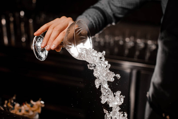 Bartender hand pouring a full cocktail glass with ice - Photo, Image