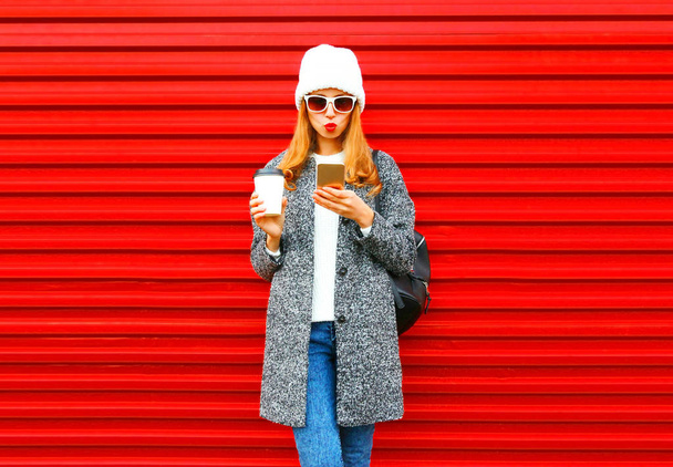 Fashion pretty young woman with coffee cup using smartphone on a - Foto, Bild