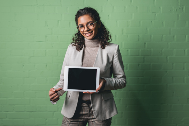 young african american businesswoman presenting digital tablet in front of green wall - Фото, изображение