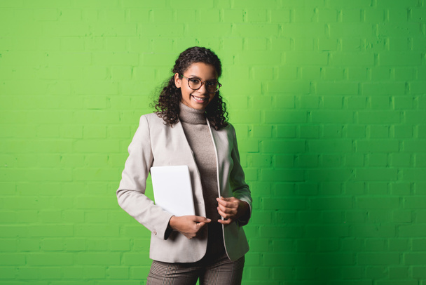 young smiling african american businesswoman with digital tablet in front of green wall - Foto, Bild