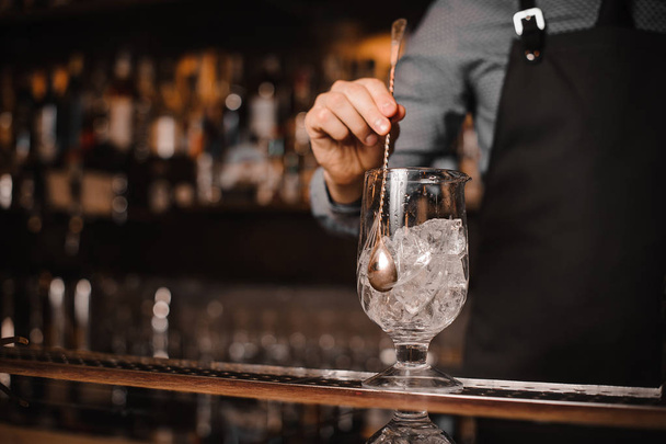 Barman stirring ice cubes with help of spoon - Photo, Image