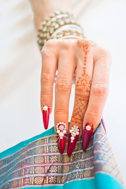 unhas decoradas com brilhante e mão com tatuagens de henna
 - Foto, Imagem