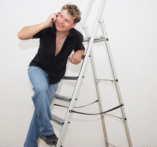 a man with a cell on a stepladder on a white background - Zdjęcie, obraz