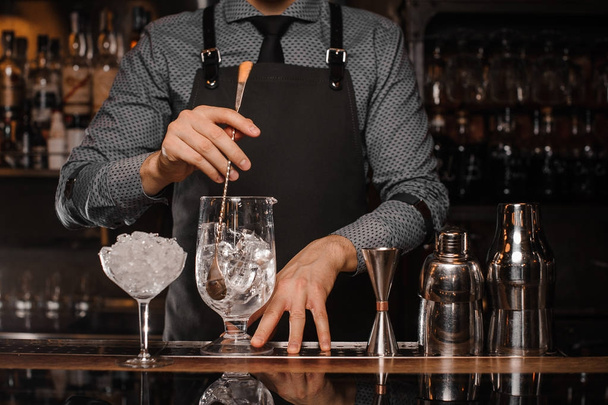 Barman making a cocktail with help of the bar equipment - 写真・画像
