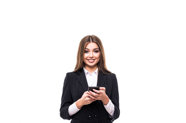 schöne junge Geschäftsfrau hält ihr Handy in der Hand und blickt in die Kamera, während sie vor grauem Hintergrund steht - Foto, Bild