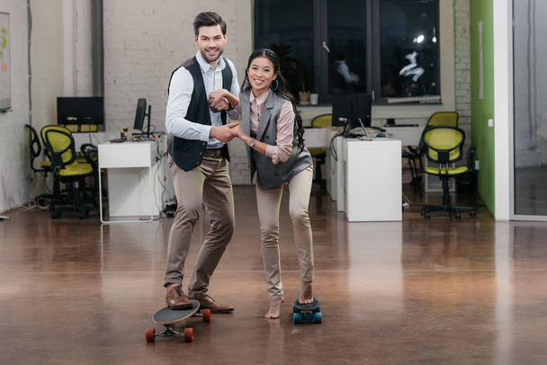 multi-etnische ondernemers hebben plezier met skateboards in kantoor - Foto, afbeelding