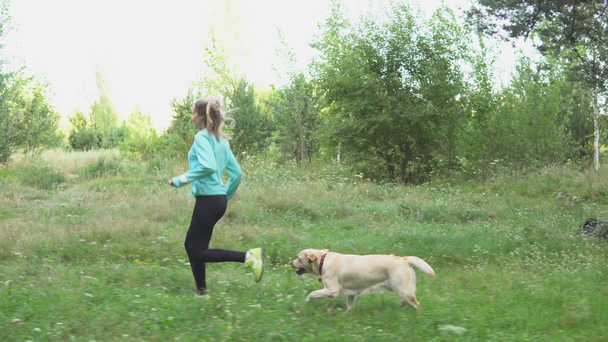 Молодая девушка бежит через лес со своей чистокровной собакой в теплый летний день
. - Кадры, видео