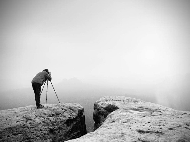 Wildlife photographer on mountain summit works. Man like to travel and photography, taking pictures - Photo, Image