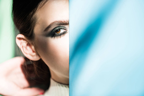 Woman or girl hide half face makeup at blue wall - Photo, image
