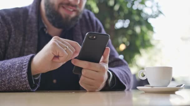 Ένας νεαρός άνδρας με ένα Smartphone στο Cafe - Πλάνα, βίντεο